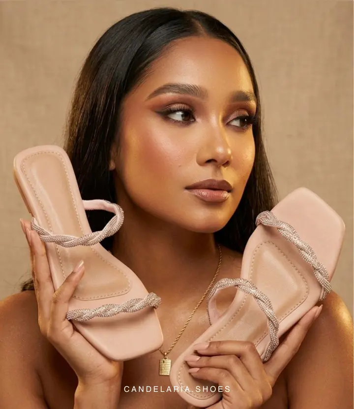 Modelo sosteniendo sandalias Candelaria color nude con tiras trenzadas